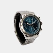 Reloj análogo de pulso metálico y tablero azul